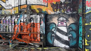 Graffiti-Kunstwerk von Michael Stevens an einer urbanen Wand in Berlin, mit einem stilisierten Auge und abstrakten Elementen, umgeben von bunten Graffiti.