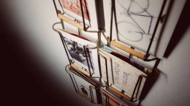 Modernes Büchereiregal mit Skizzen, Notizbüchern und Büchern, dekorativ an der Wand montiert, ideal für kreative Arbeitsräume oder Wohnzimmer.