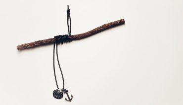 Nahaufnahme eines Schiffsknotens mit Anker und Seil, symbolisch für Seefahrt und maritime Themen, auf weißem Hintergrund.