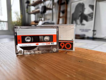 Vintage Kassette auf Holz Tisch, mit einem modernen Hintergrund, zeigt den Retro-Charme der 80er Jahre. Perfekt für Nostalgie- und Musikliebhaber.