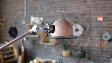 Alte Industrielampe mit rostigem Metall und Holzarm, stilvoll im Vintage-Design. Perfekt für Loft- und Wohnraumdekoration, bietet warmes Licht und einen rustikalen Charme.